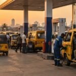 Commercial buses and tricycles queuing for petrol at a Lagos filling station at sunset